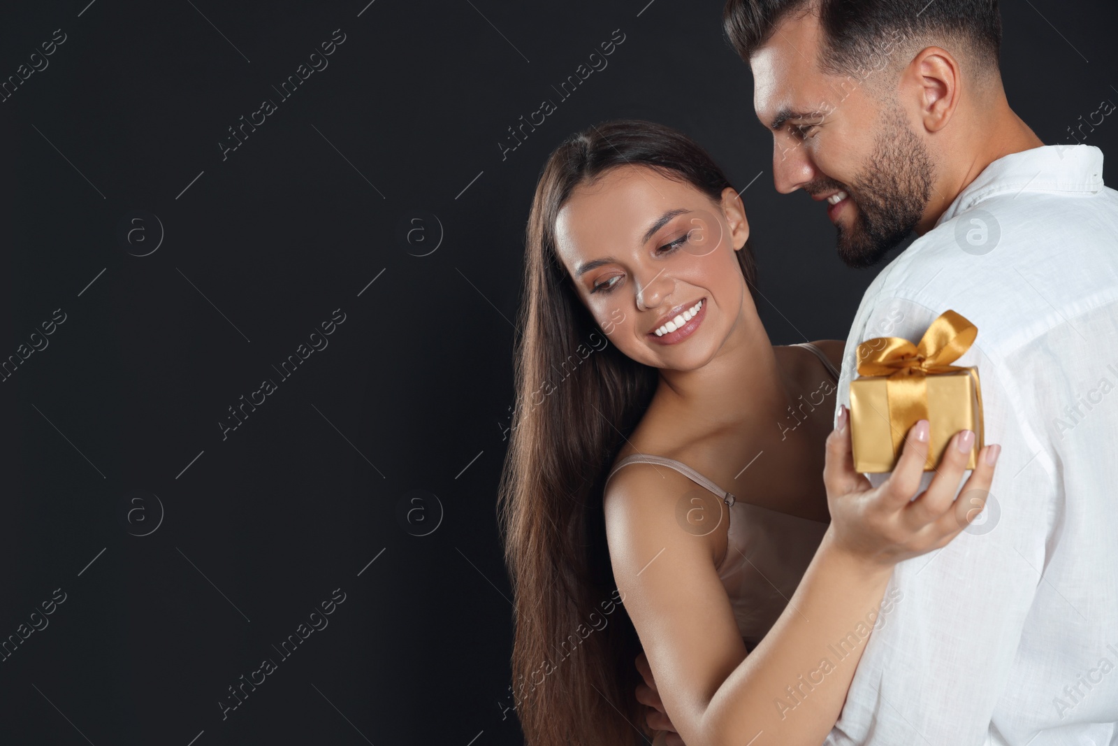 Photo of Woman presenting gift to her boyfriend on black background