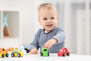 Photo of Children toys. Cute little boy playing with toy cars at white table in room