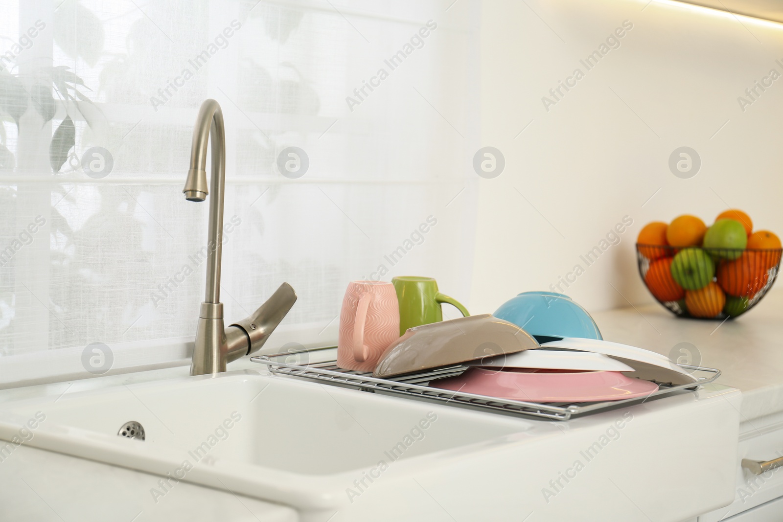 Photo of Drying rack with clean dishes over sink in kitchen