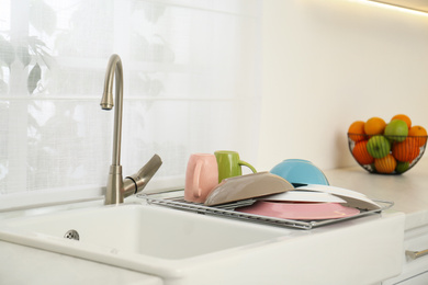 Photo of Drying rack with clean dishes over sink in kitchen