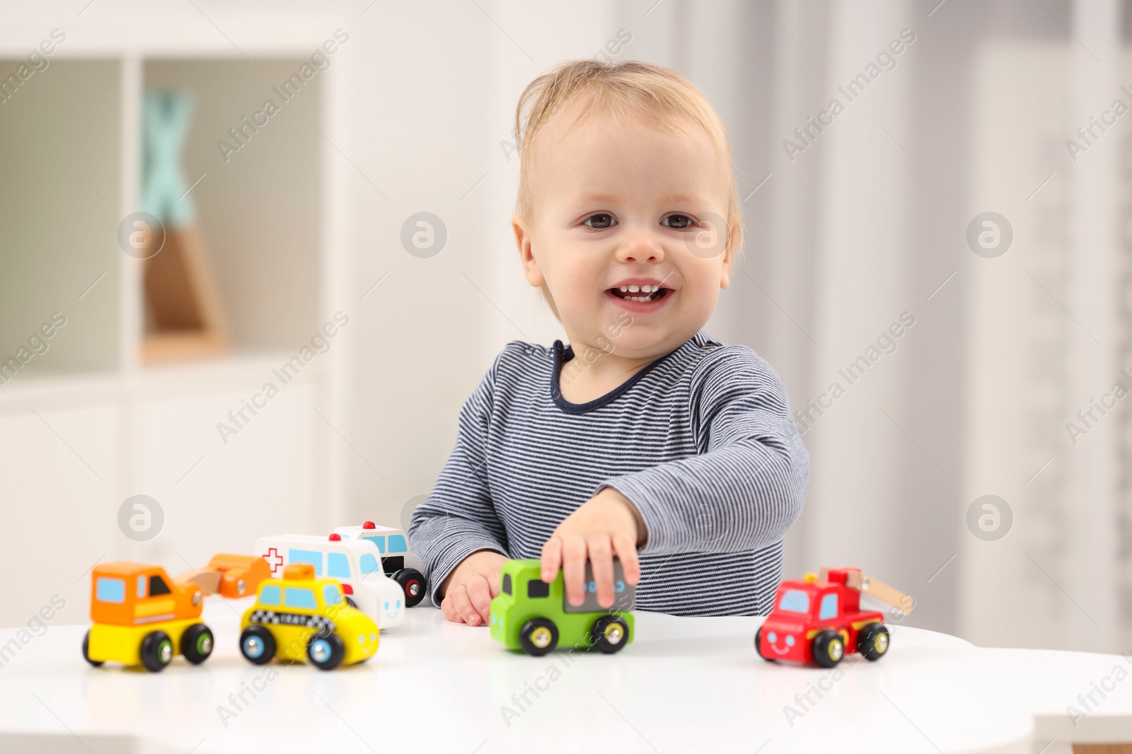 Photo of Children toys. Cute little boy playing with toy cars at white table in room