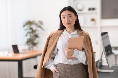 Portrait of beautiful businesswoman with tablet in office. Space for text