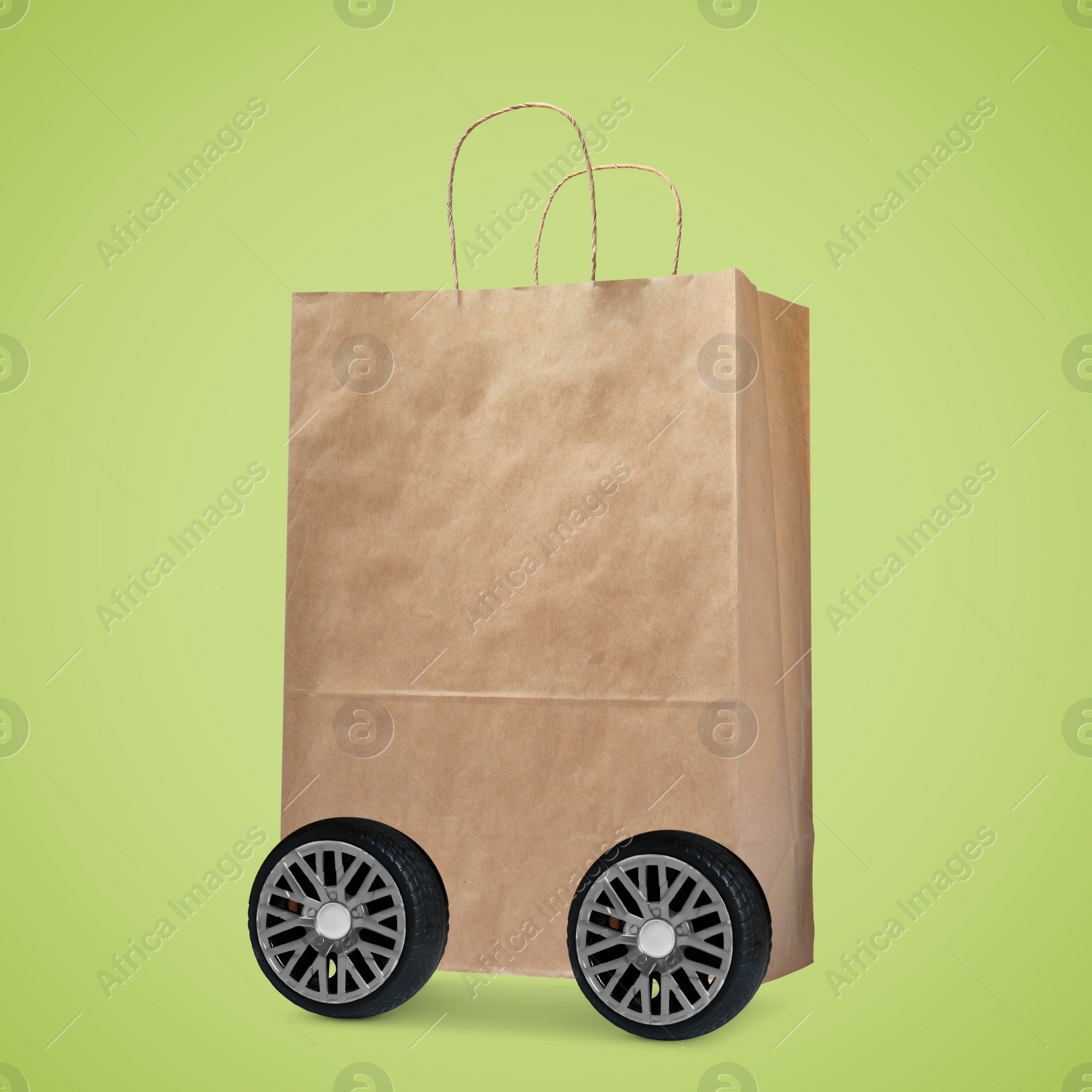 Image of Paper shopping bag on wheels against yellowish green background. Delivery service