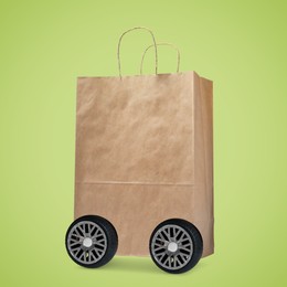 Paper shopping bag on wheels against yellowish green background. Delivery service