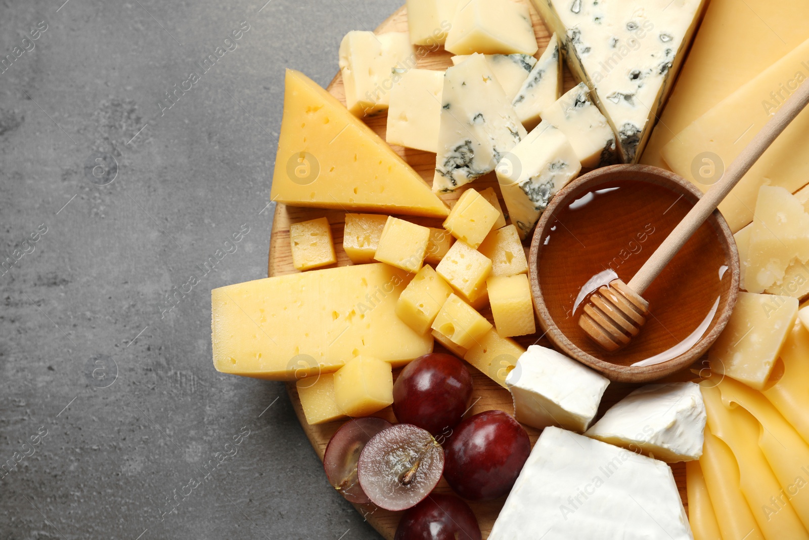 Photo of Different types of delicious cheese and snacks served on grey table, top view