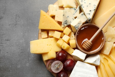 Different types of delicious cheese and snacks served on grey table, top view