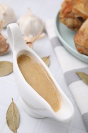 Photo of Delicious turkey gravy in sauce boat on white table, closeup