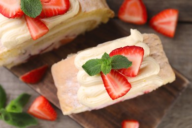 Pieces of delicious cake roll with strawberries and cream on table, top view