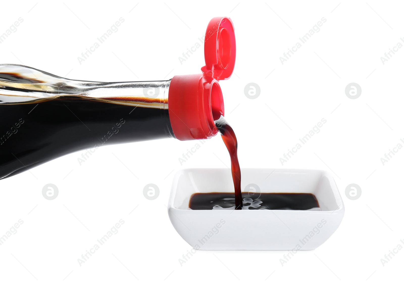 Photo of Pouring soy sauce into bowl against white background