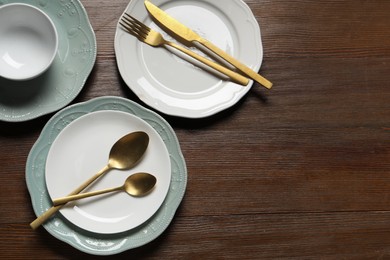 Photo of Beautiful ceramic dishware and cutlery on wooden table, flat lay. Space for text