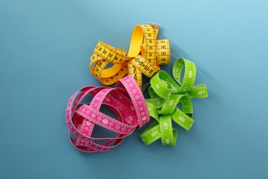 Photo of Kit of different measuring tapes on light blue background, flat lay