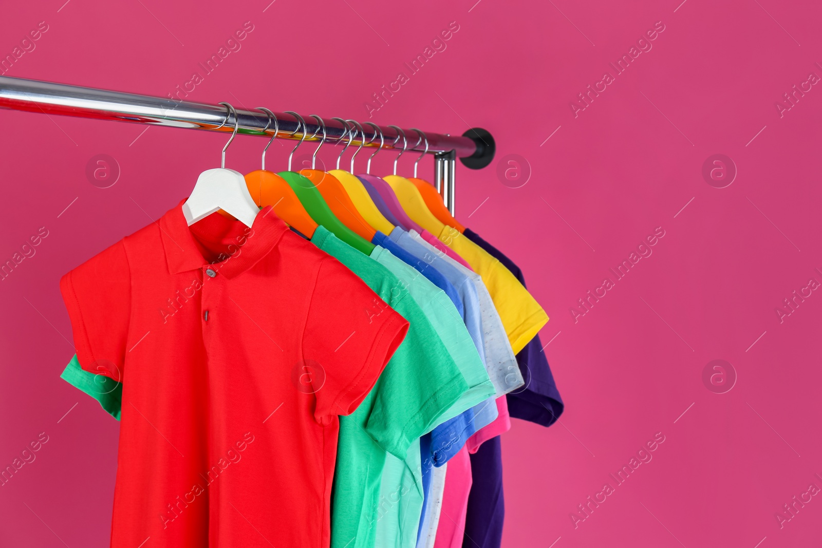 Photo of Rack with stylish children clothes on pink background. Space for text