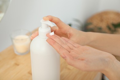 Photo of Woman applying body cream on hand in room, closeup