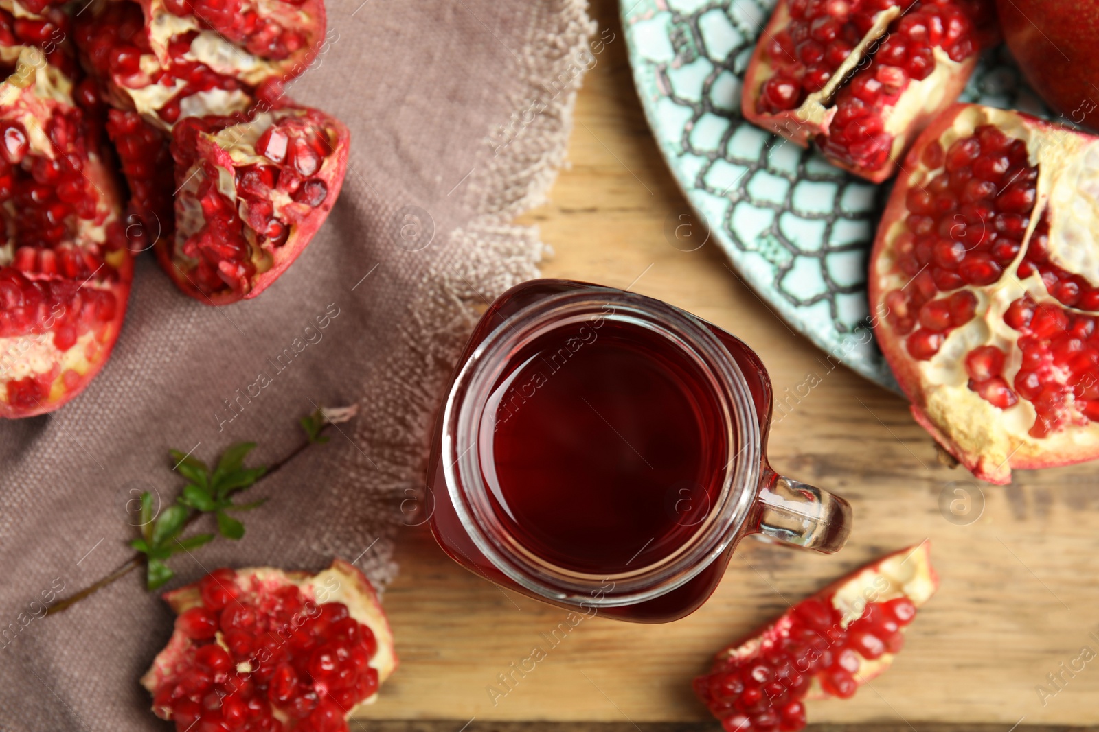 Photo of Pomegranate juice in mason jar and fresh fruits on wooden table, flat lay