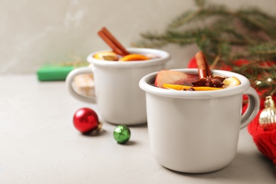 Photo of Cups of tasty mulled wine on grey table. Space for text