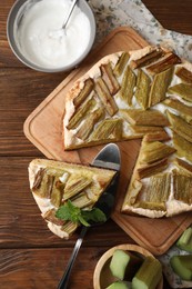 Photo of Freshly baked rhubarb pie and cake server on wooden table, flat lay