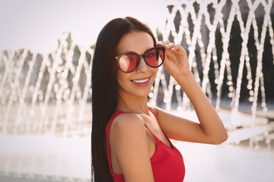 Beautiful young woman wearing stylish sunglasses outdoors