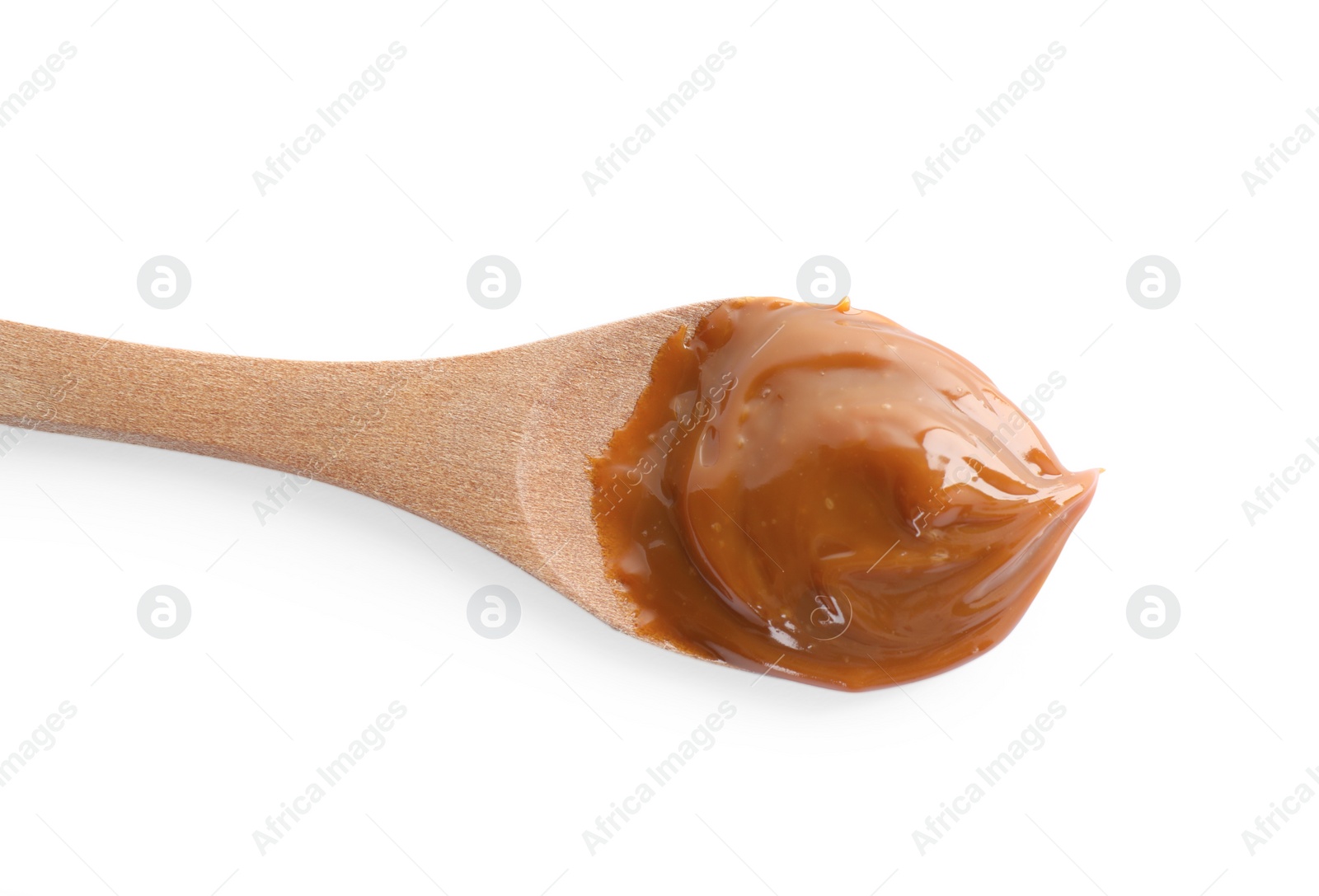 Photo of Wooden spoon with tasty boiled condensed milk isolated on white, top view