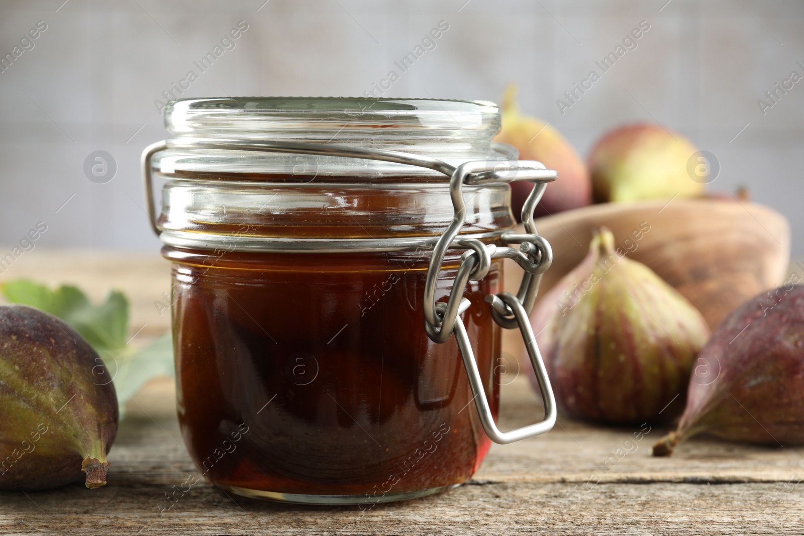 Photo of Jar of tasty sweet jam and fresh figs on wooden table