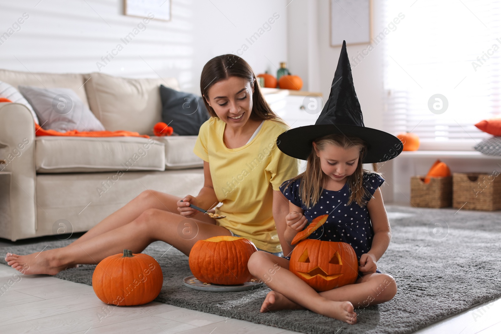 Photo of Mother and daughter making pumpkin jack o'lanterns at home. Halloween celebration