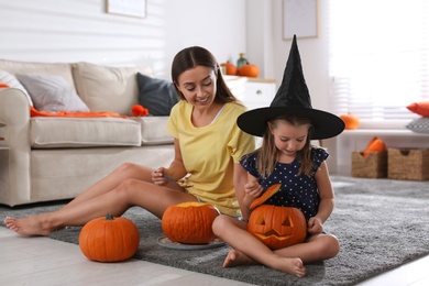 Photo of Mother and daughter making pumpkin jack o'lanterns at home. Halloween celebration