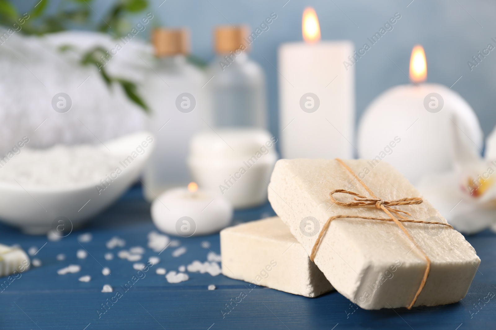 Photo of Soap bars and sea salt on blue wooden table, closeup with space for text. Retreat concept