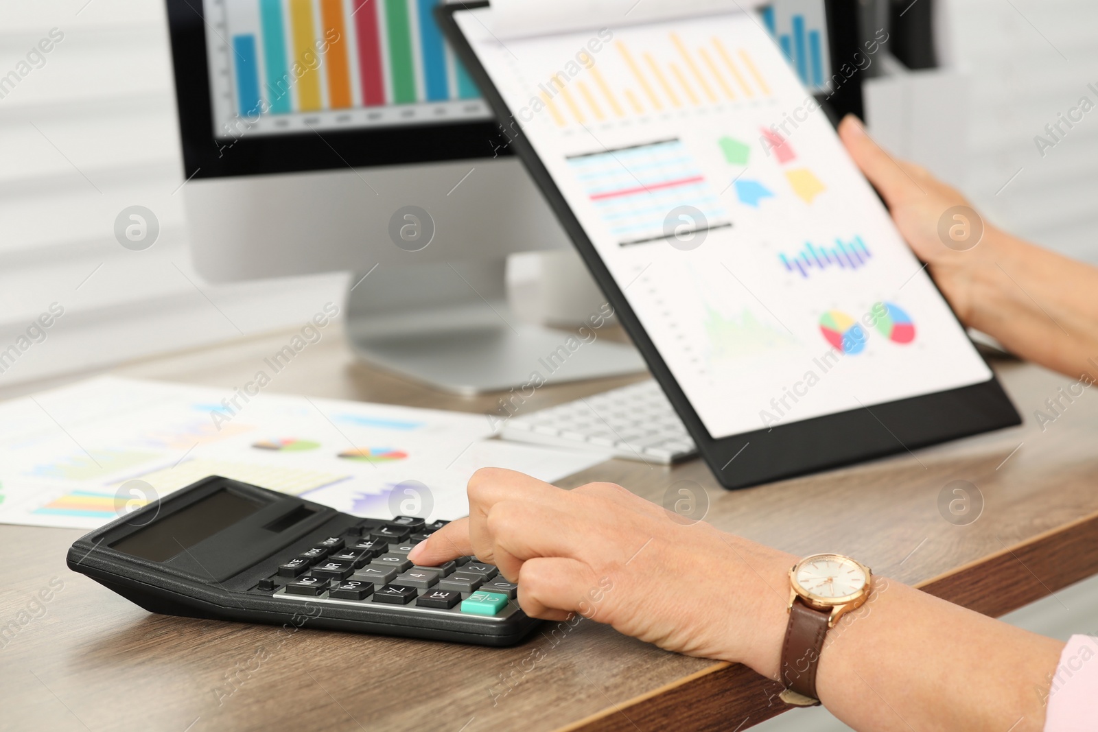 Photo of Accountant using calculator at wooden desk in office, closeup