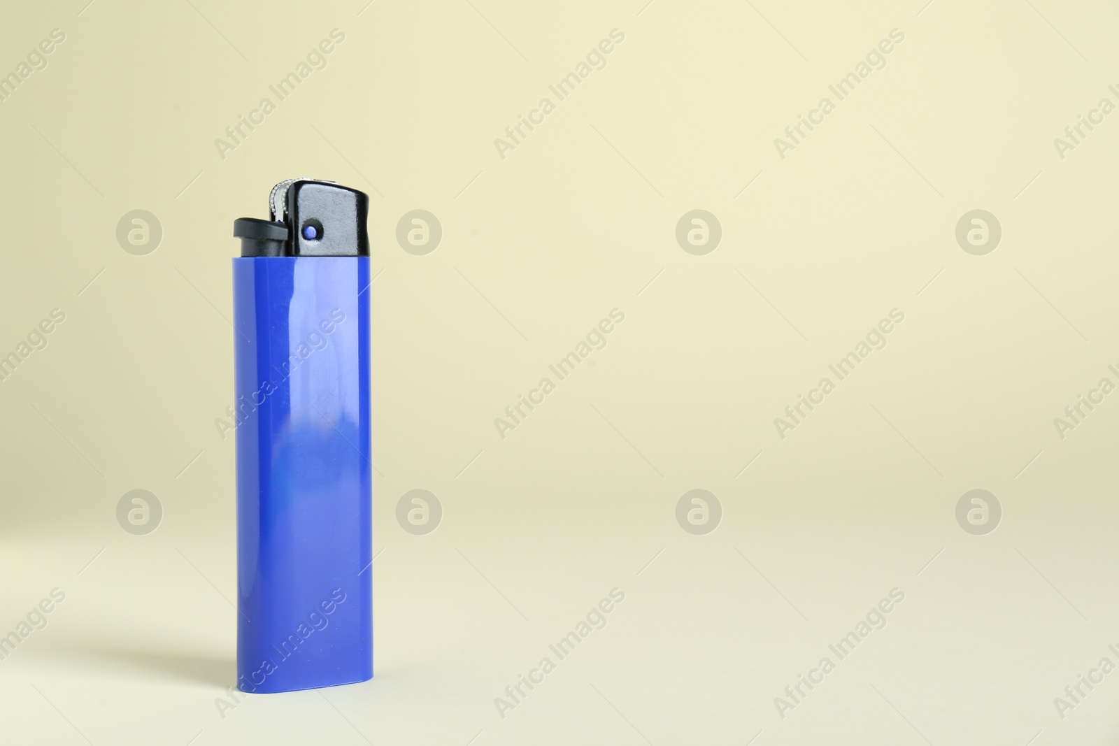 Photo of Stylish small pocket lighter on beige background, space for text