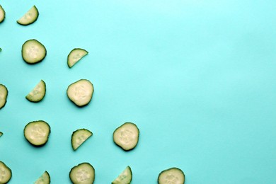 Photo of Slices of fresh ripe cucumber on turquoise background, flat lay. Space for text