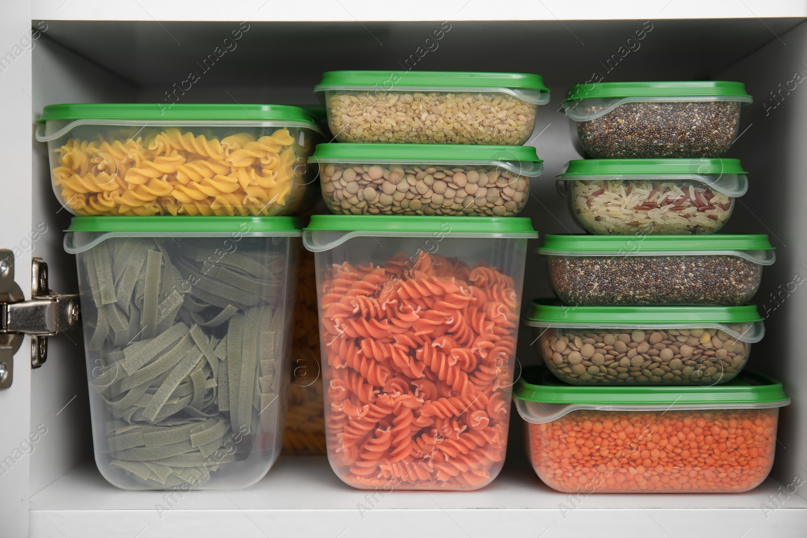 Photo of Plastic containers filled with food products in kitchen cabinet, closeup