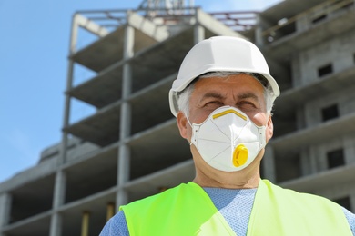Professional builder in safety equipment at construction site, space for text