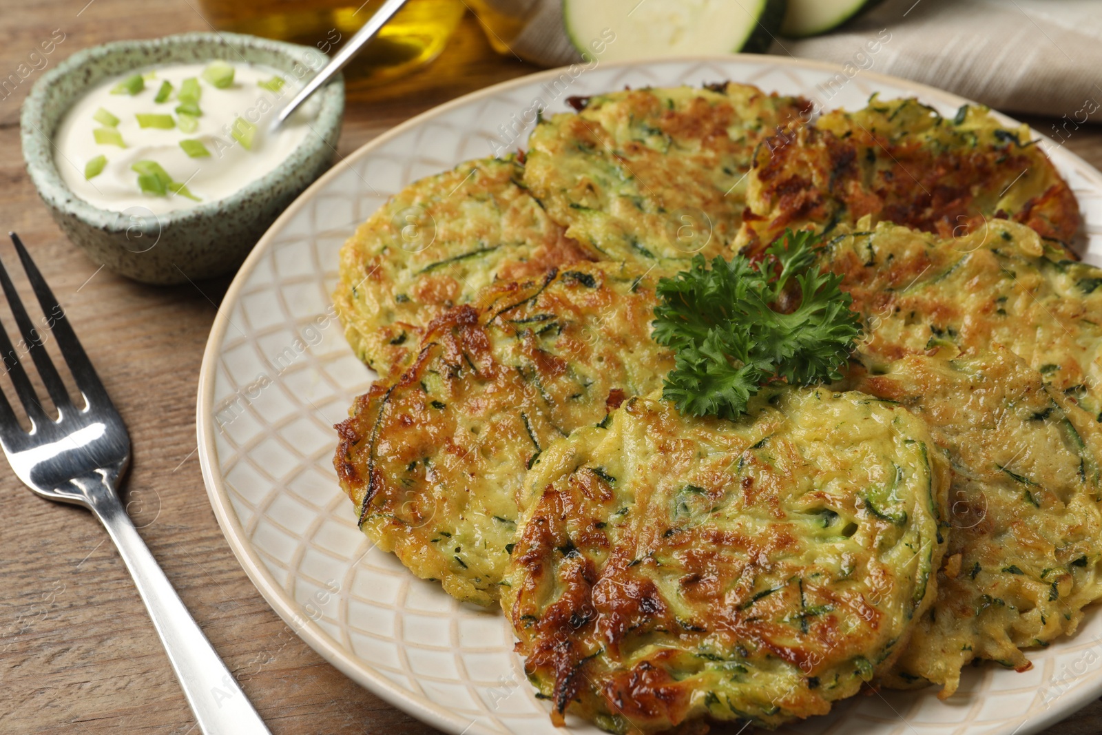 Photo of Delicious zucchini fritters served on wooden table, closeup