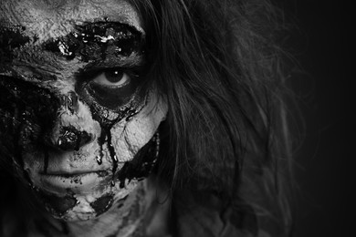 Photo of Scary zombie on dark background, black and white effect. Halloween monster