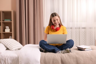 Online learning. Teenage girl with laptop on bed at home