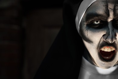 Photo of Portrait of scary devilish nun on blurred background, closeup with space for text. Halloween party look