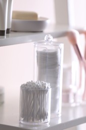 Cotton buds and pads in transparent holders on shelf