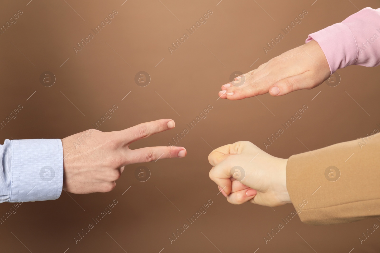 Photo of People playing rock, paper and scissors on brown background, closeup