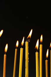 Photo of Many burning church candles on black background