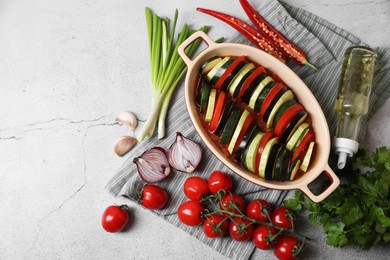 Cooking delicious ratatouille. Dish with different cut vegetables on light grey table, flat lay. Space for text