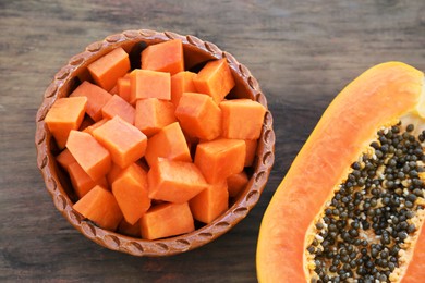 Photo of Tasty ripe cut papaya fruits on wooden table, flat lay