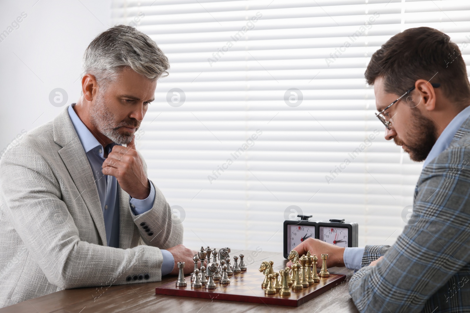 Photo of Men playing chess during tournament at table indoors