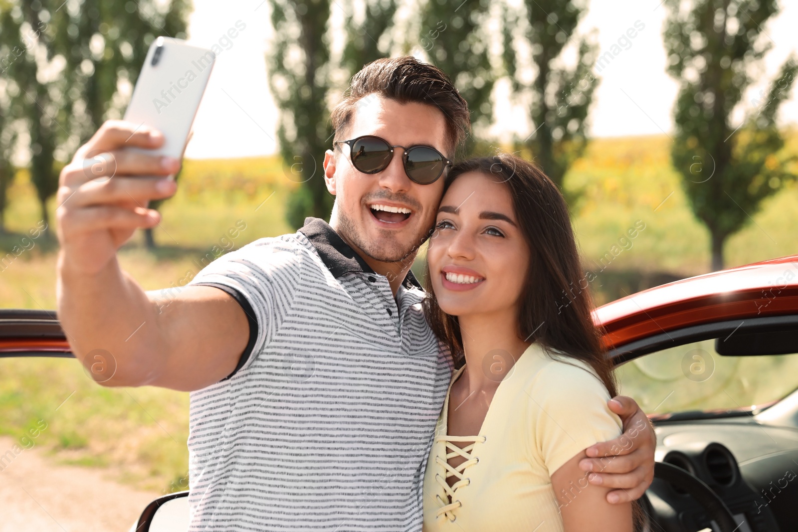 Photo of Happy young couple taking selfie near car on road