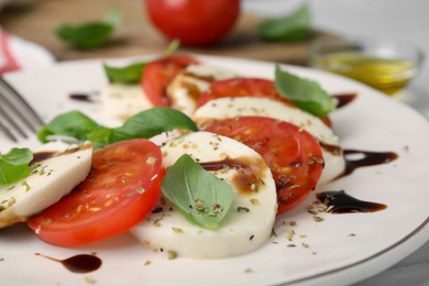 Photo of Delicious Caprese salad dressing with balsamic vinegar on plate, closeup