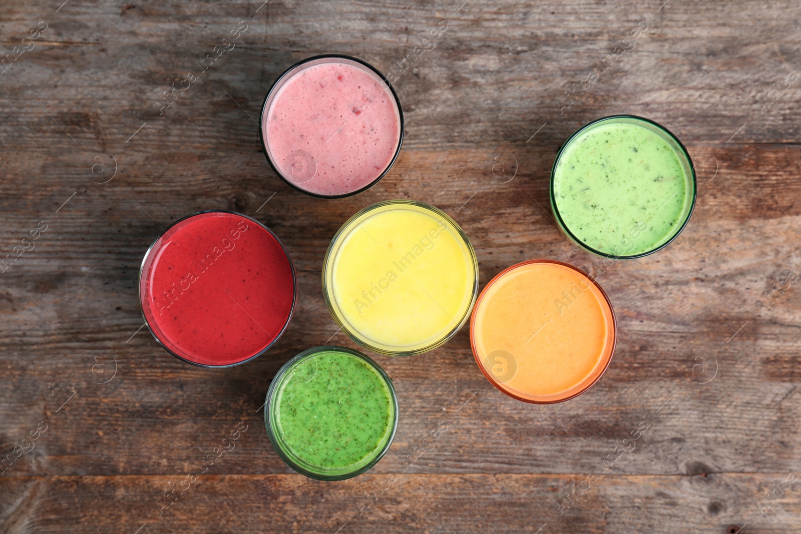 Photo of Glasses with delicious detox smoothies on wooden background, top view