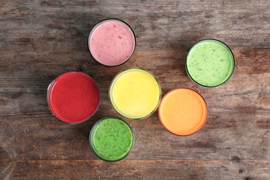 Glasses with delicious detox smoothies on wooden background, top view