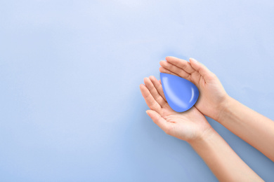 Image of Woman holding water drop on blue background, top view with space for text. Ecology protection
