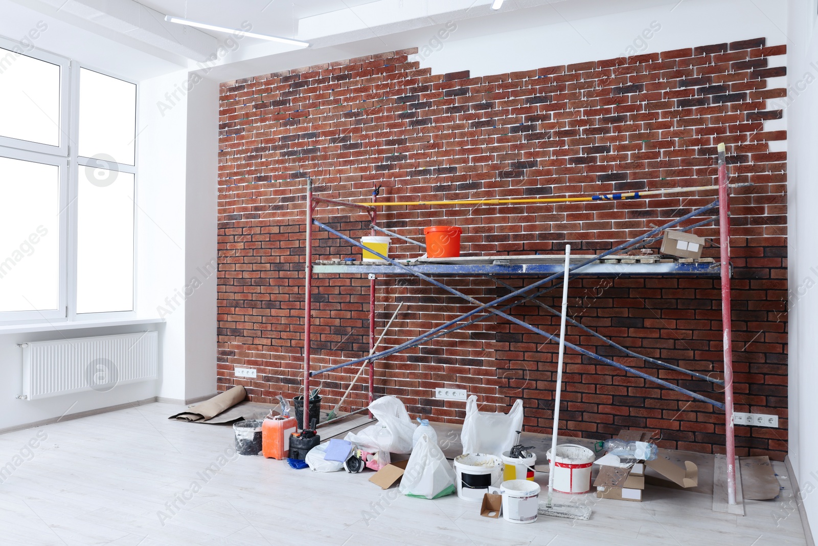 Photo of Scaffolding with equipment near brick wall in repaired room