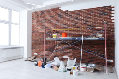 Photo of Scaffolding with equipment near brick wall in repaired room