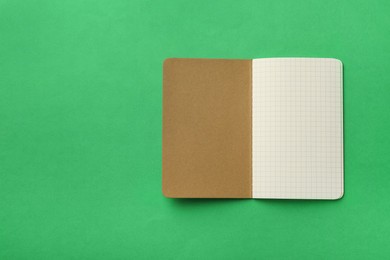 Stylish open notebook with blank sheets on green background, top view. Space for text