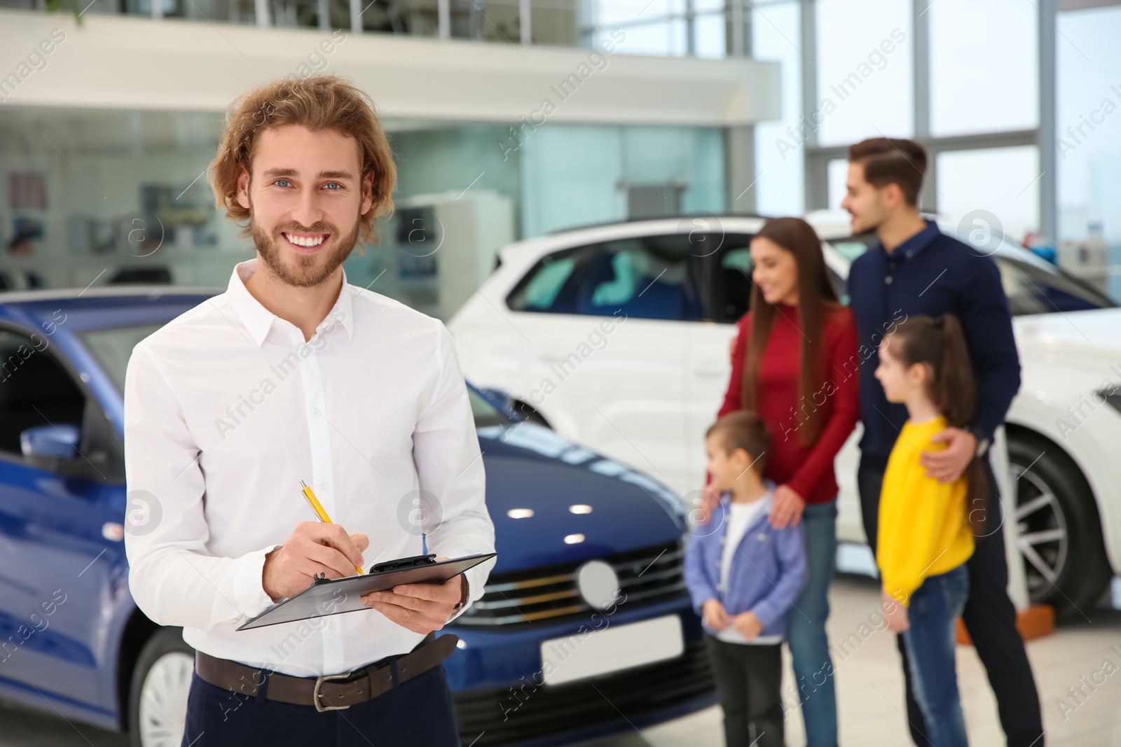 Photo of Car salesman with clipboard and blurred family near auto on background